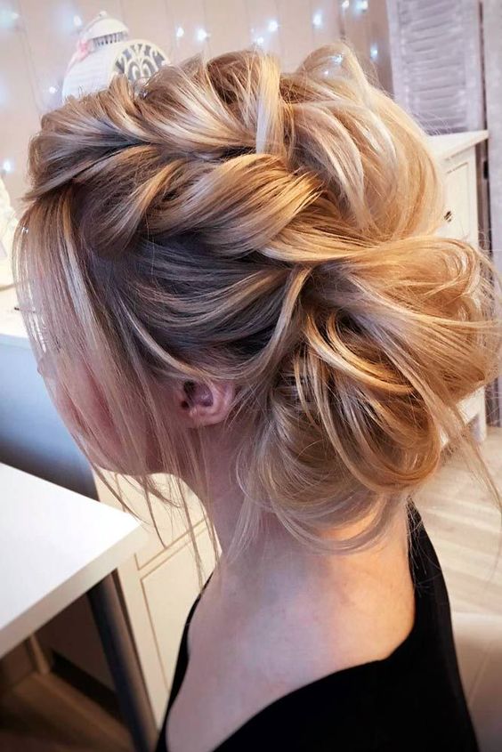 a voluminous messy braided updo with some locks down for a cute and glam look