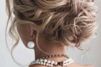 a beautiful and messy wavy wedding low bun with a wavy top, some locks down is a gorgeous idea for long hair