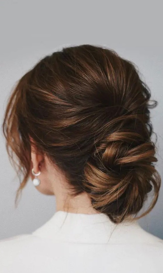 a chic low ballerina bun with a bump on top and face-framing locks is a cool idea for a wedding