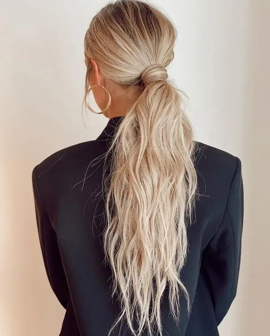 a classy messy and textural low ponytail with a messy top and hair wrapping it is a cool idea for a modern bride or bridesmaid look