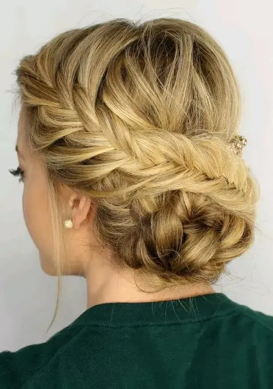 a fishtail side braided updo with a braided bun and some locks down is a creative idea for a boho wedding