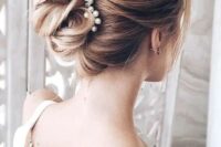 a gorgeous twisted wedding updo secured with a pearl hairpiece and with volume on top is a lovely idea for a refined wedding