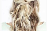 a half updo with a braided halo and waves down is a romantic and trendy option