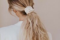 a low and messy ponytail wrapped up in pearls is a chic idea for a modern or minimalist bride or bridesmaid