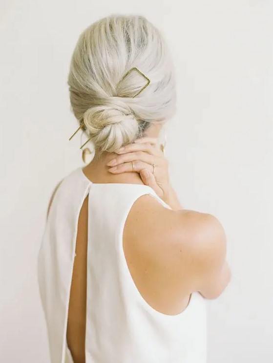 a low bun with a bump and an oversized gilded accessory is ideal for a minimalist bride or bridesmaid
