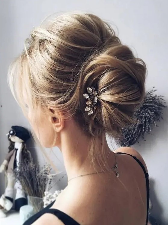 a messy chignon hairstyle with bangs and a rhinestone hairpiece for a modern casual bride or bridesmaids