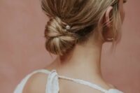 a messy low bun with a bump on top and a pearl hair pin, with some locks down, is a chic and cool hairstyle