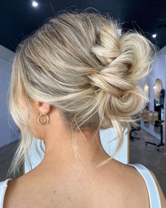 a messy twisted chignon with a bump on top and some locks down, plus some face-framing locks is a cool idea for a wedding