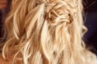 a messy wavy half updo with a braided halo and a braided knot for a relaxed and boho look