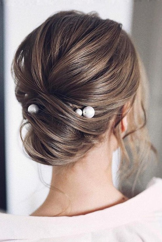 an effortlessly chic twisted updo with a volume on top and some locks down accented with large pearl pins