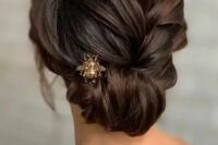 an elegant braided low updo with a twisted halo and a gold bug hairpiece is a very stylish and chic idea
