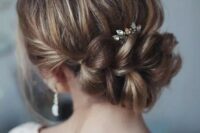 an elegant updo with a large braided element, a bump and a rhinestone hairpiece for a romantic feel, for a bride or bridesmaid