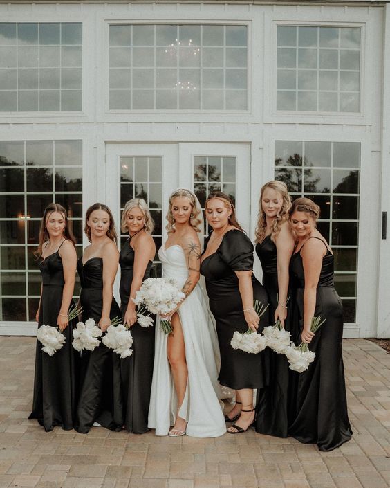 mismatching black maxi and midi bridesmaid dresses with various necklines and black shoes for a modern wedding