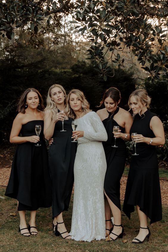 mismatching midi black bridesmaid dresses and black strappy shoes are a great combo for a boho wedding