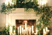 02 a beautiful fireplace with candles inside, around and on the mantel, with lush greenery and white blooms