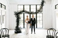 03 The wedding ceremony space was all-white, done with black chairs and a dark greenery garland as a backdrop