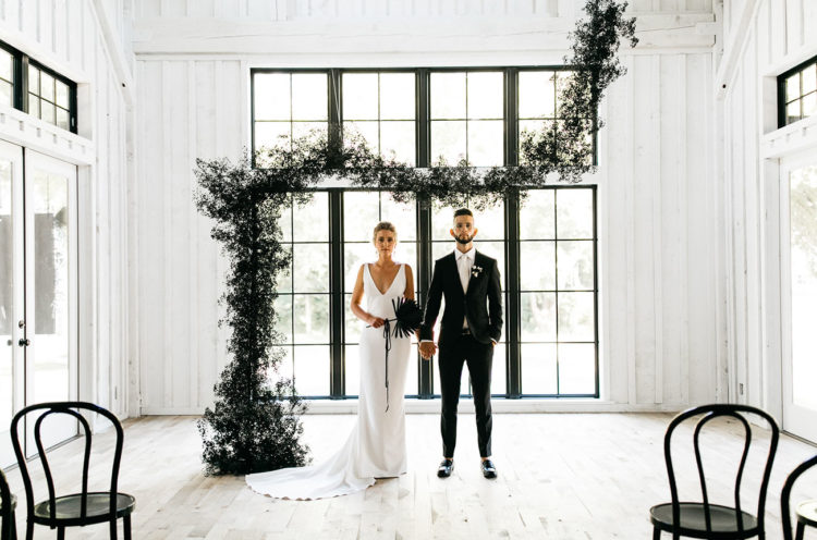 The wedding ceremony space was all-white, done with black chairs and a dark greenery garland as a backdrop