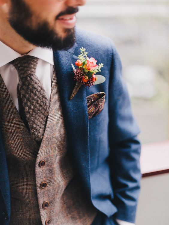 a blue suit with a brown checked waistcoat and a brown woollen necktie plus a patterned handkerchief