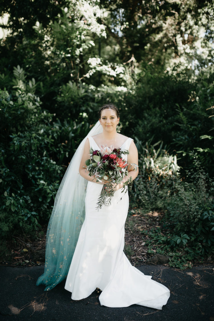 The bride was wearing a plain fit and flare wedding gown with a deep neckline and a gorgeous blue ombre veil