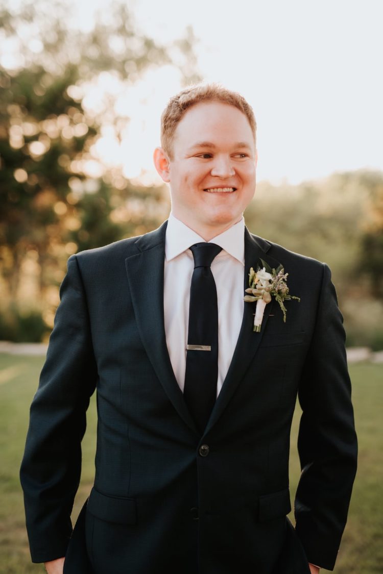 The groom was wearing a black suit with a black tie plus a floral boutonniere