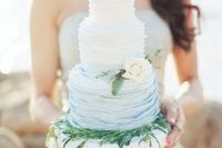 07 an ombre blue ruffle wedding cake decorated with greenery and a white bloom for an oceanside wedding