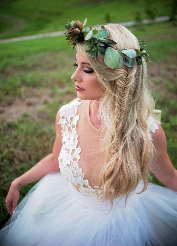a textural half updo with a side fishtail braid and a greenery and succulent crown for a boho bride