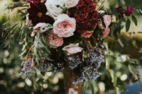 09 a lush floral centerpiece of burgundy, blush and white blooms, textural greenery in a gold vase