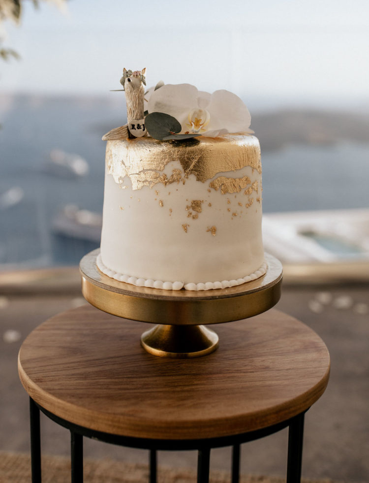 The wedding cake is a white one with gold leaf, topped with a white orchid