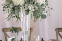 10 a lush floral centerpiece of eucalyptus and white hydrangeas in a tall glass vase