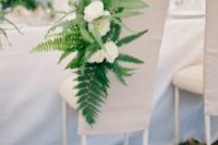 11 a fabric covered chair decorated with ferns and white blooms is a creative idea
