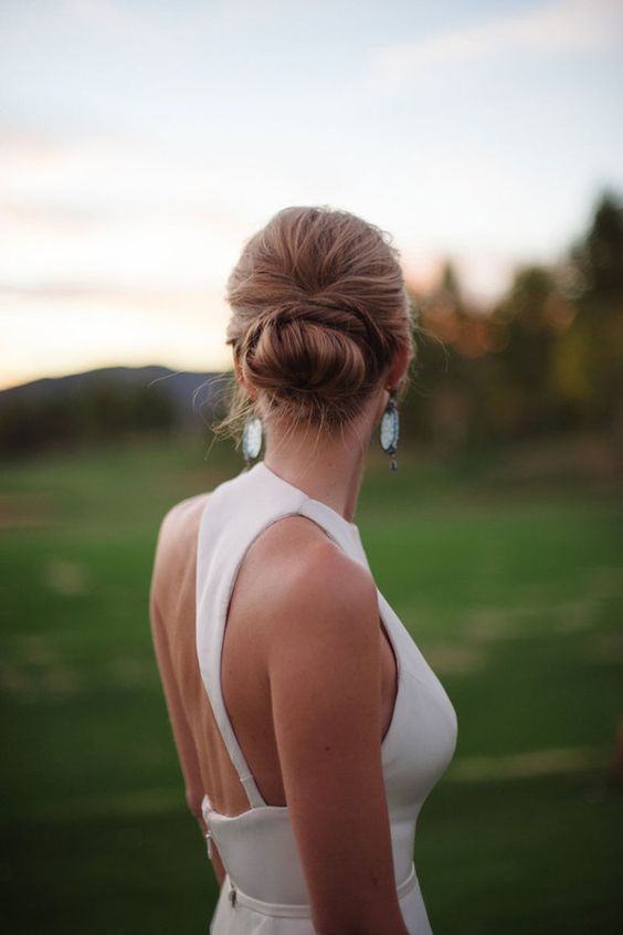 a twisted low bun on long hair and a bump on top for a chic modern bridal look