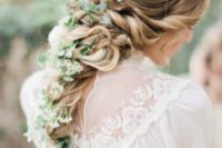 13 a twisted and curled braid with a texture on top and greenery and whiet blooms in the braid