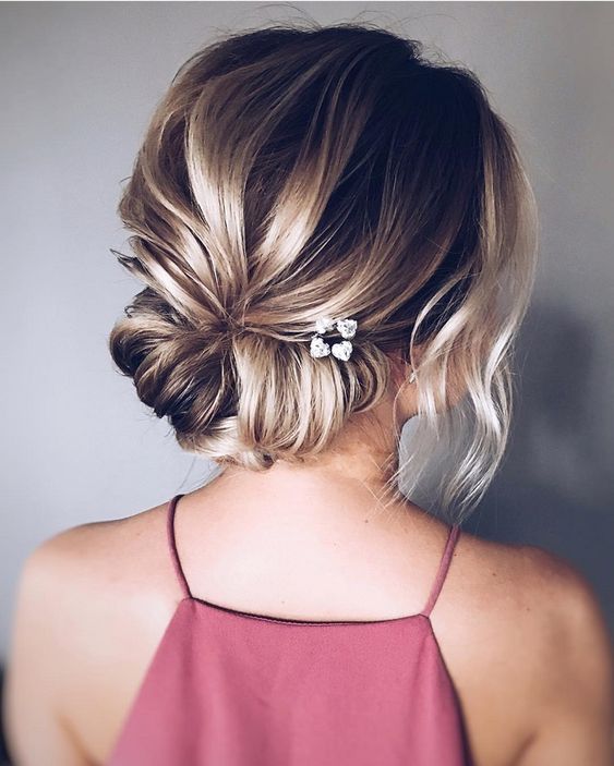 a low twisted chignon with a bump, some locks down and little blooms tucked in