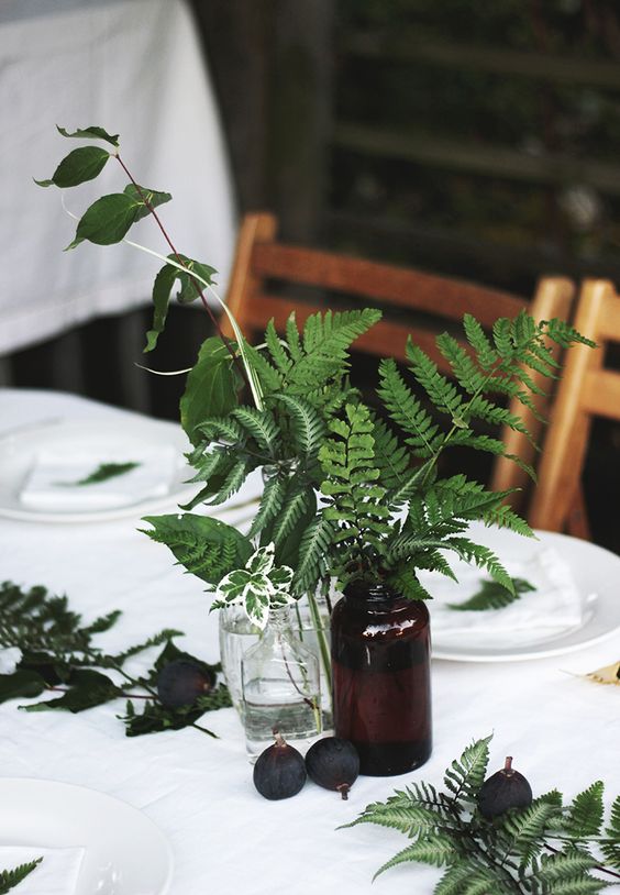 a table setting done with figs and ferns and foliage in vases and bottles for fresh fall feel