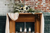 20 a faux wooden mantel with an airy runner, contrasting florals on the mantel and candles inside it
