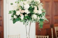 20 an elegant wedding centerpiece of white and blush blooms plus greenery in a tall clear glass vase