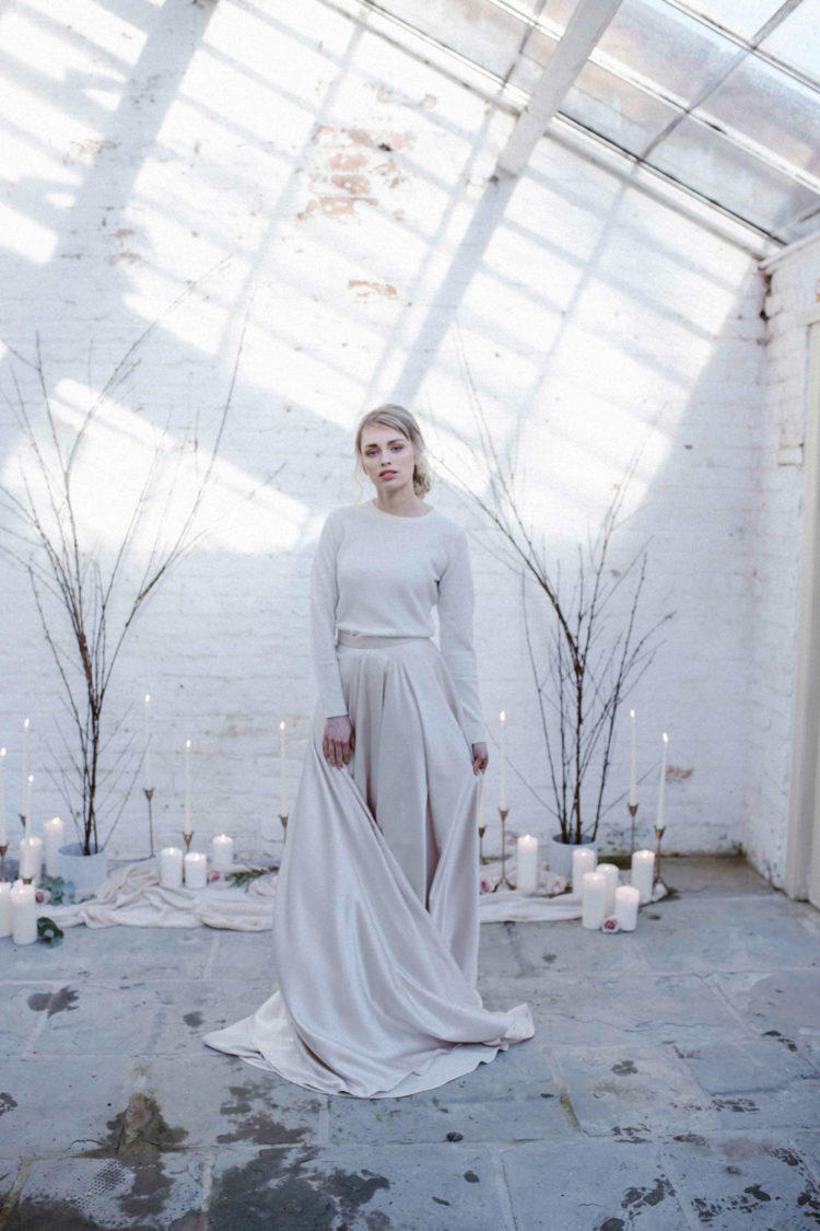 a minimalist wedding ensemble with a plain pleated skirt and a neutral top with long sleeves