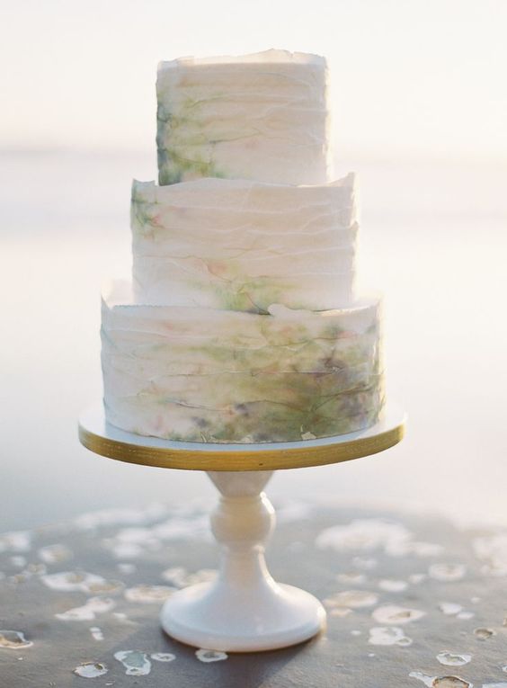 a ruffle wedding cake done in white and coastal shades - green, purple, yellow
