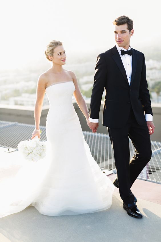 a strapless plain wedding gown with a layered skirt and a train and no other detailing for a modern glam bride