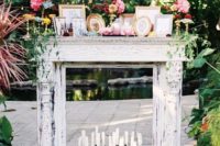 a shabby chic white mantel with lots of candles in the bottles, photos in frames and bright blooms