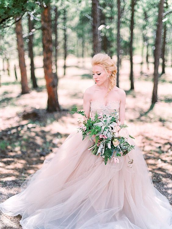 a strapless princess-style wedding gown with a layered tulle skirt and a lace bodice in tender blush color