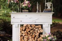 26 a vintage white mantel with candles, bloom decor and firewood stacked inside the mantel