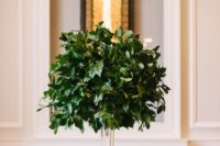 29 an ultra-modern tall centerpiece of a clear vase and foliage looks amazing and follows the non-floral wedding trend