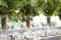 31 such tall lush textural greenery centerpieces in clear vases create a feeling of outdoors right in your venue