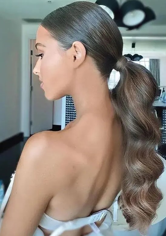 a beautiful and elegant wavy low ponytail with a sleek and shiny top is a stylsih idea for a glam look