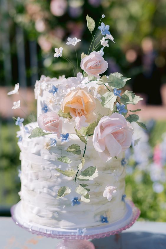 a beautiful white ruffle wedding cake decorated with pastel blooms and leaves looks really subtle and will be perfect for a spring wedding