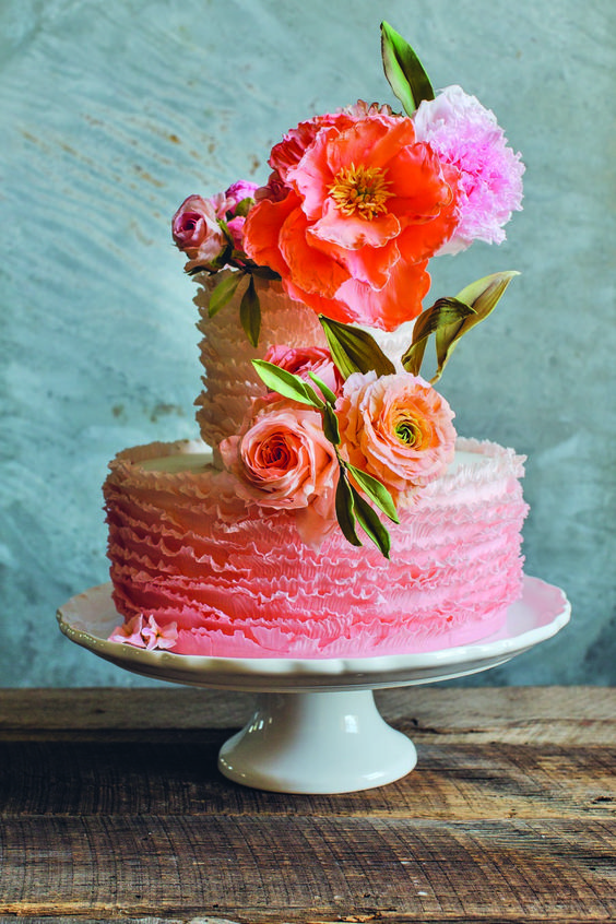 a bright pink ruffle wedding cake topped with bold blooms and leaves looks amazing, bold and bright