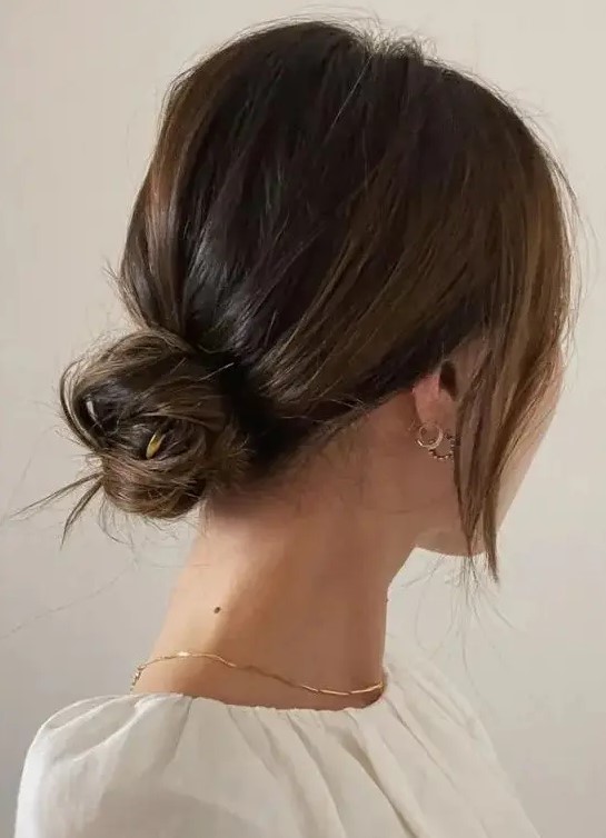 A chic and cool messy low bun with a bump on top and face framing locks is a cool hairstyle for medium hair