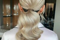 a cool low modern ponytail with a volume on top and wavy hair down is a cool idea for a modern wedding guest