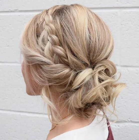 a cool messy and curly low updo with a braided halo and some locks and curls down for a boho or rustic wedding